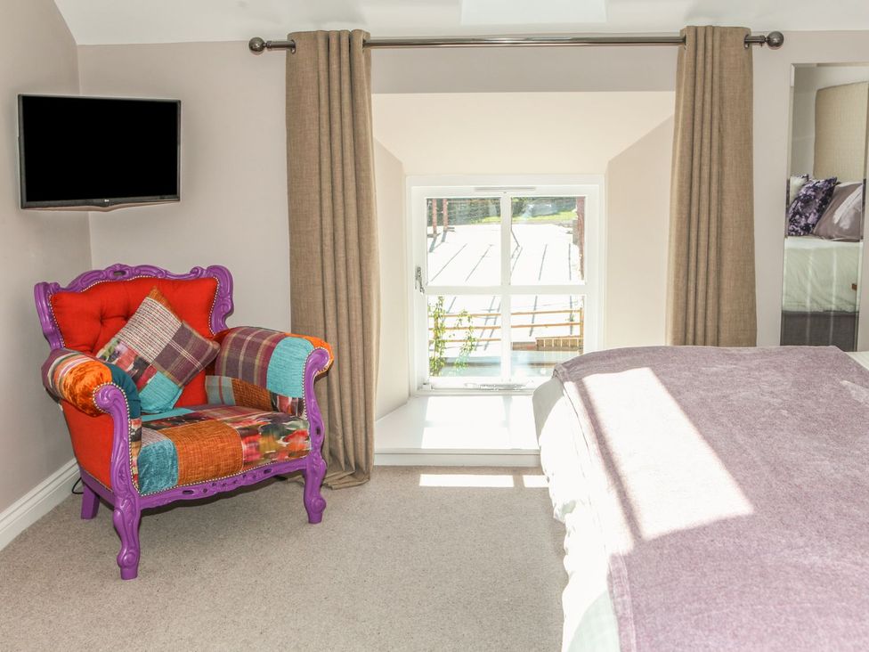 A bedroom with an armchair and television at The Granary in Durham