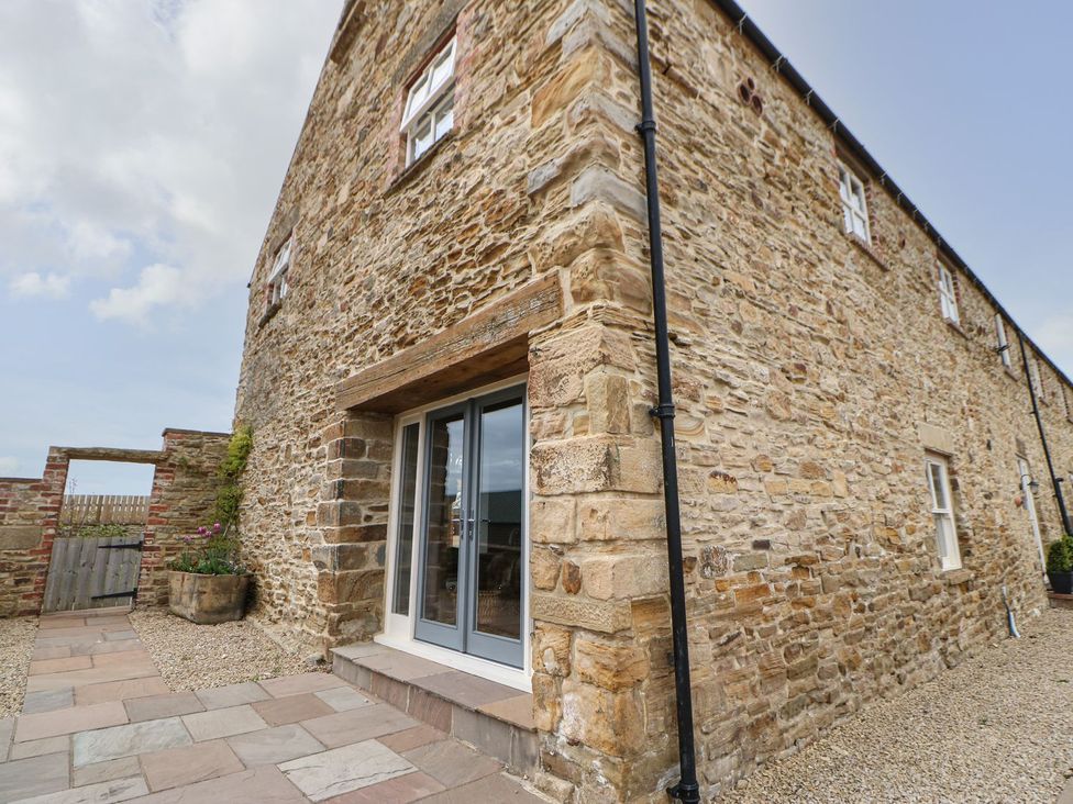 An outdoor area with stone walls and a paved pathway at The Granary in Durham