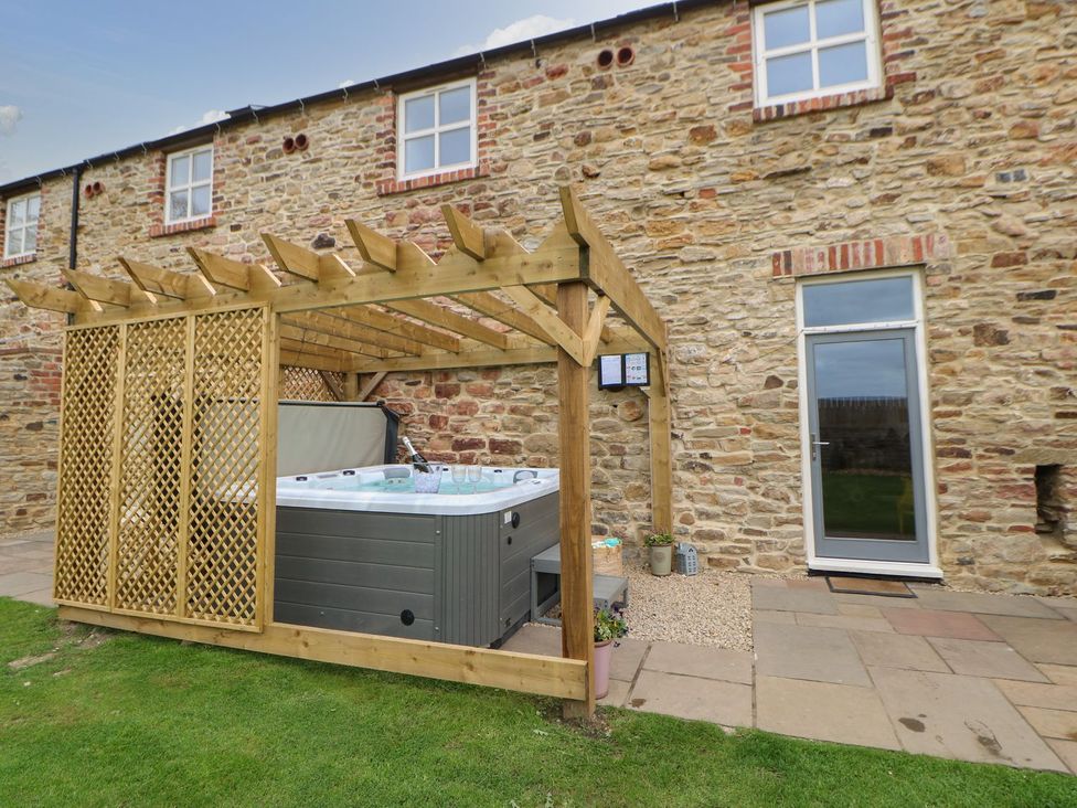 A garden with a hot tub under a pergola at The Granary in Durham