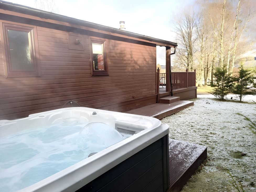 A hot tub beside a wooden cabin at Cabin 1 Moffat Manor in Moffat