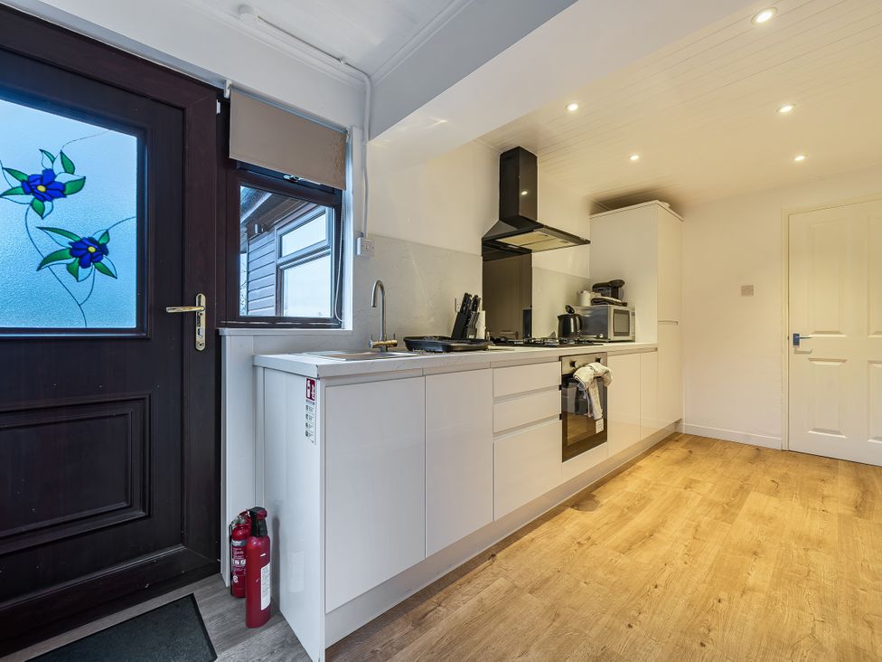 A kitchen with cabinets, stove, sink, and microwave at Cabin 1 Moffat Manor Beaufort