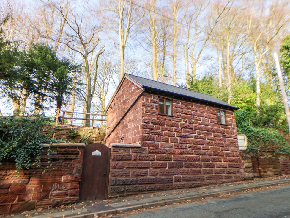 A stone building with a window and door beside trees at The Apple Store in Tarporley