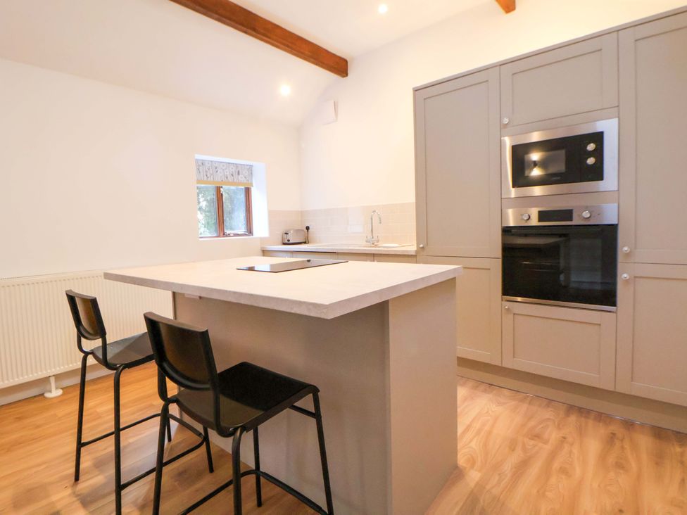 A kitchen with an island and stools at The Apple Store in Tarporley
