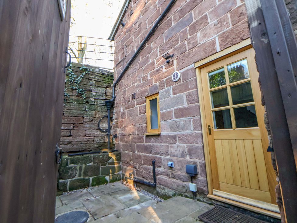 An outdoor area with a stone wall and a wooden door at The Apple Store in Tarporley