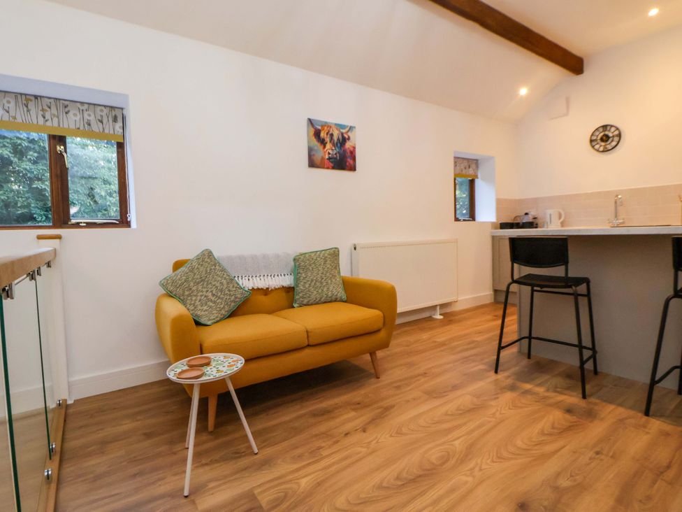 A living room with a yellow couch and kitchen island at The Apple Store in Tarporley