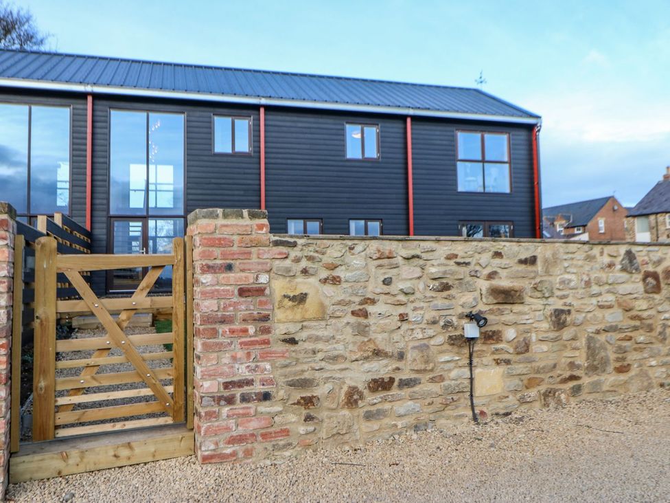 An outdoor area with a stone wall and a wooden gate at Stackyard in Durham