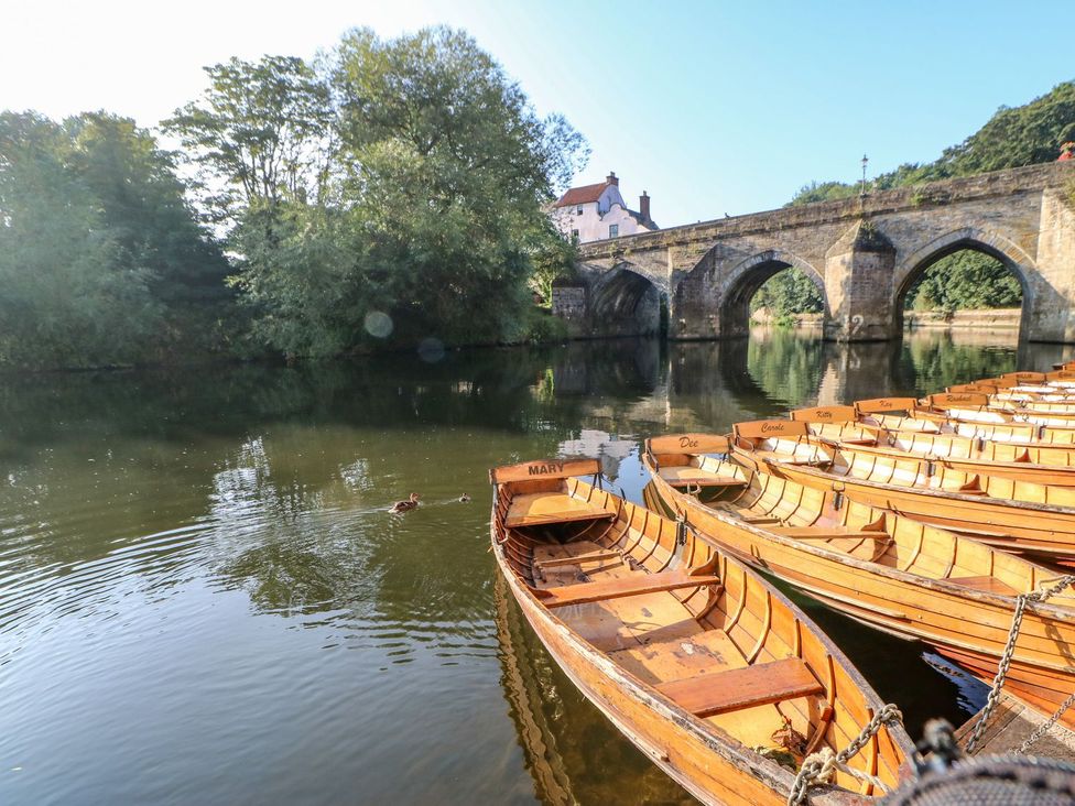 Wooden boats on a river under a stone bridge at Stackyard Durham