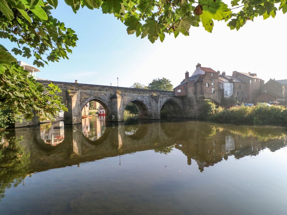 A bridge over water with houses and trees at Stackyard in Durham