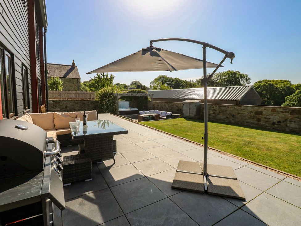 A patio with a table and sofa at Stackyard Witton Gilbert