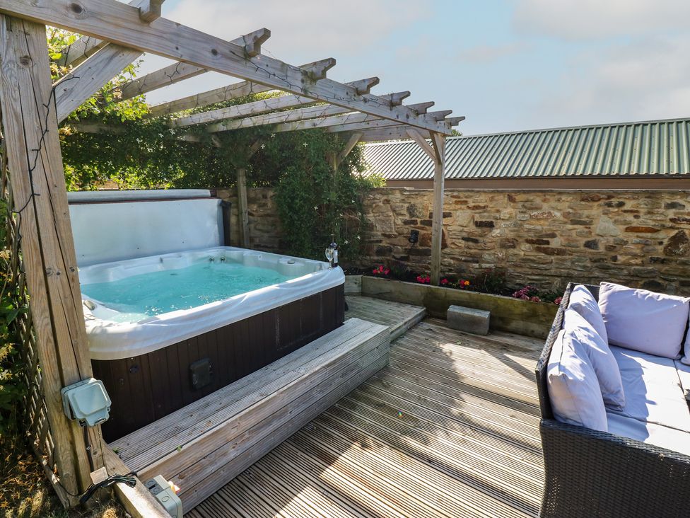 A hot tub and seating area on a wooden deck at Stackyard Witton Gilbert