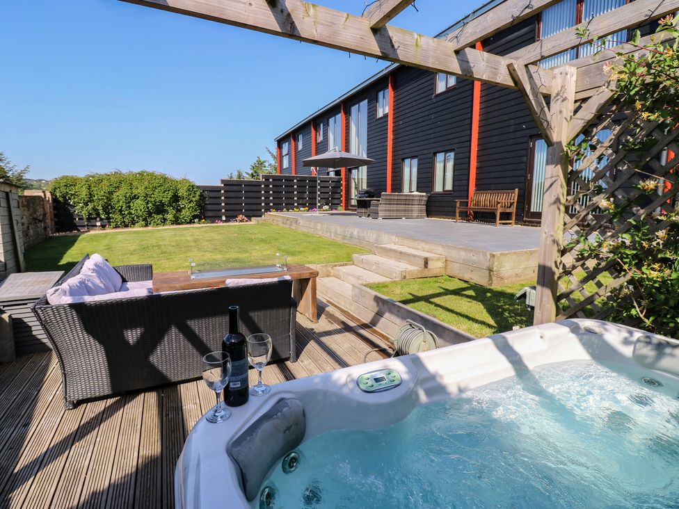 A garden with a hot tub and outdoor seating at Stackyard Witton Gilbert
