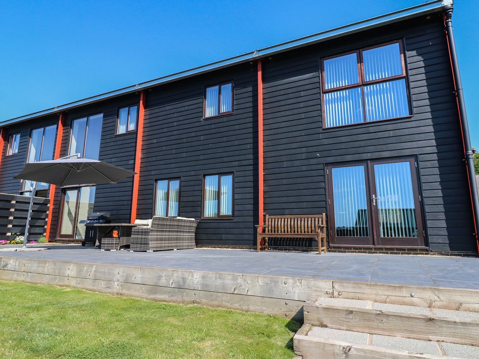 An outdoor area with a house, patio furniture and an umbrella at Stackyard in Witton Gilbert