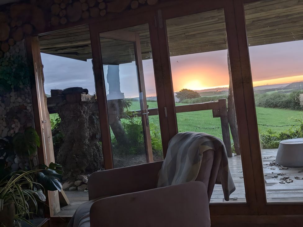 A room with a glass door and view of a sunset at The Retreat Cabin in Llanelli