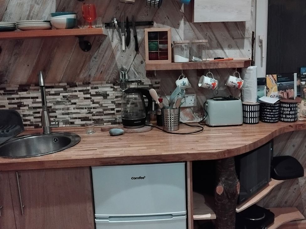 A kitchen with a sink, coffee maker, and refrigerator at The Retreat Cabin in Llanelli