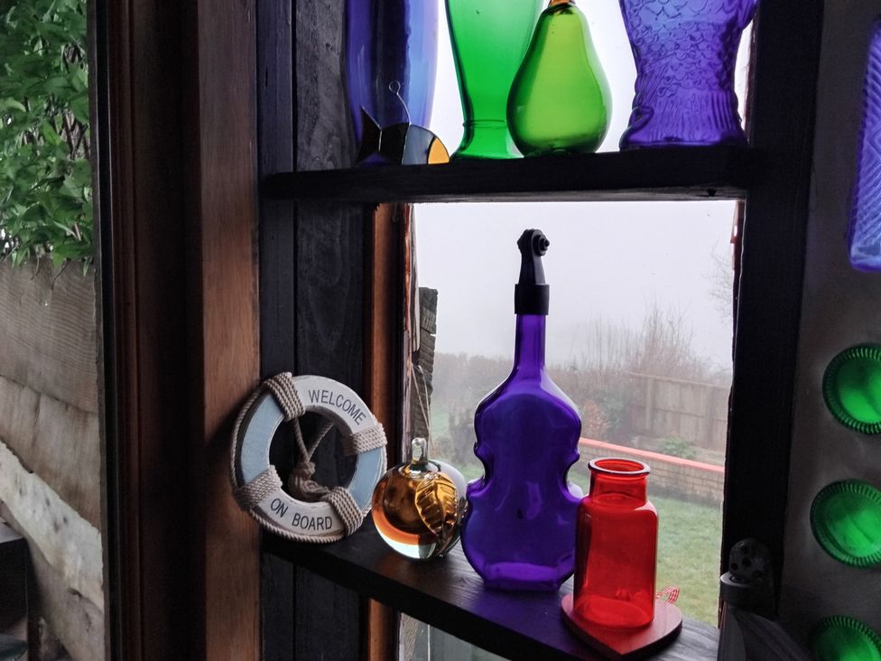 A collection of colorful bottles and a welcome sign on a window at The Retreat Cabin in Llanelli