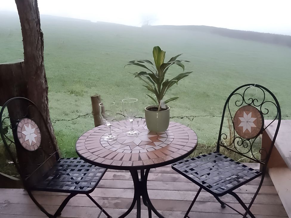 A table with two chairs and glasses on a patio at The Retreat Cabin in Llanelli
