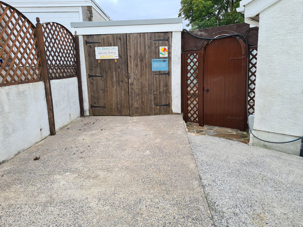 A gated entryway with a wooden gate and fence at The Retreat Cabin in Llanelli