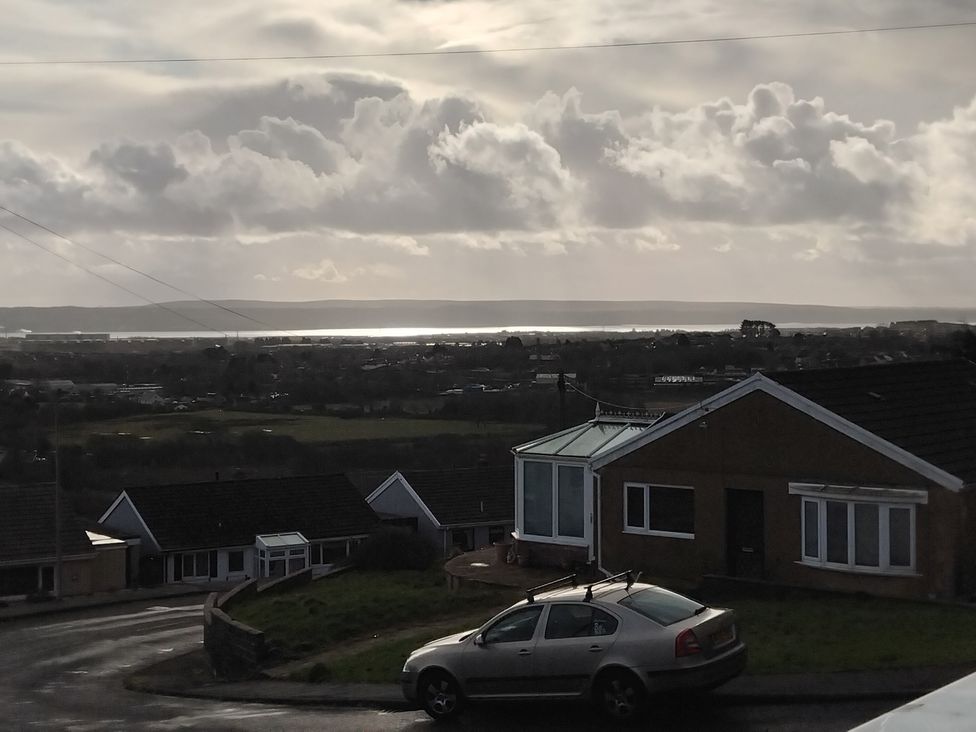 A view of houses and a car with a cloudy sky in the background at The Retreat Cabin in Llanelli
