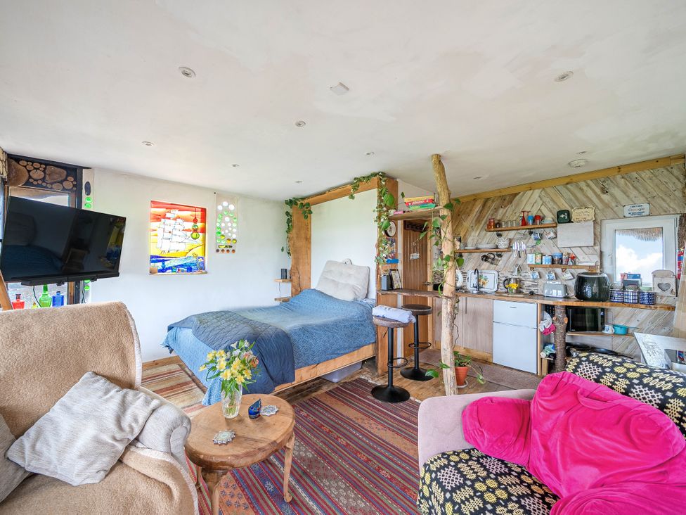 A studio with a bed, sofa, and kitchen area at The Retreat Cabin in Llanelli