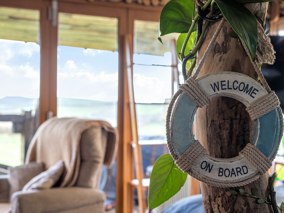 A lifebuoy hanging next to a plant and a chair at The Retreat Cabin in Llanelli