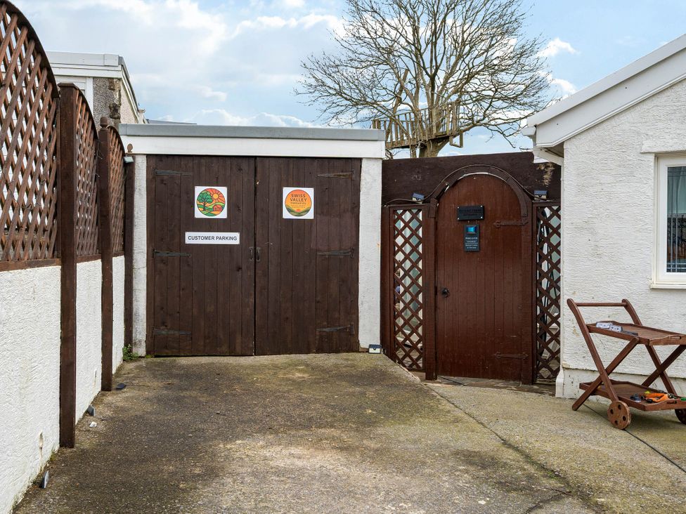 An outdoor area with a wooden gate and signs at The Retreat Cabin in Llanelli
