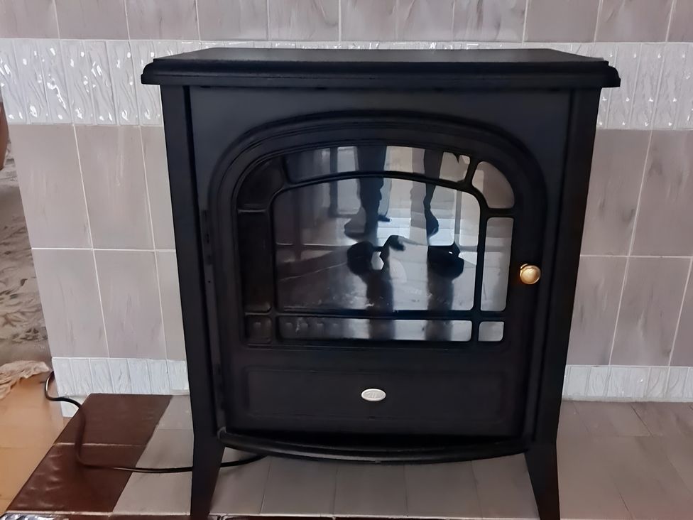 A stove with a glass front in a living room at Erisgeir on Isle of Mull