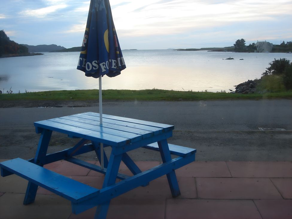 A blue picnic table with an umbrella by the water at Erisgeir Isle of Mull