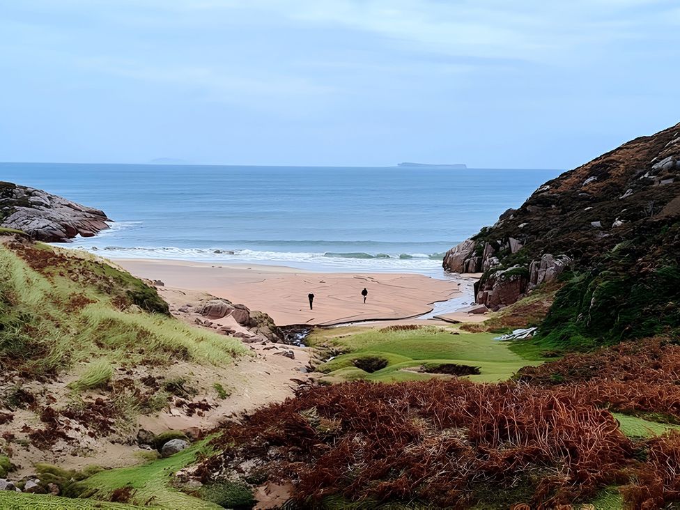 A beach scene with people walking near the water at Erisgeir Isle of Mull