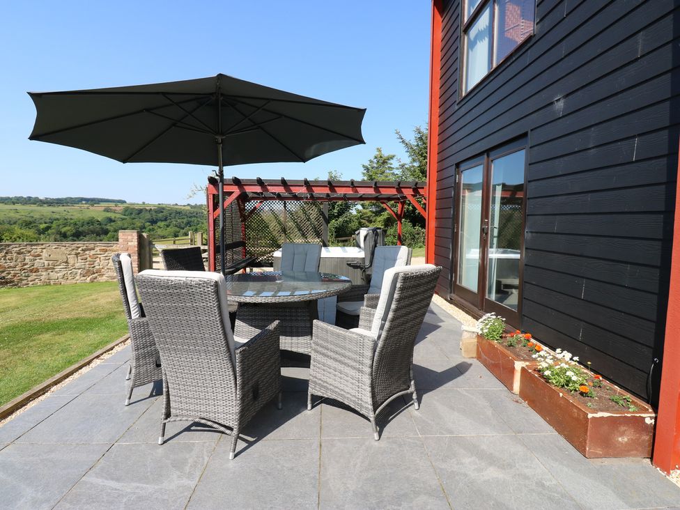 An outdoor patio with a table and chairs under an umbrella at High Church Hill in Witton Gilbert