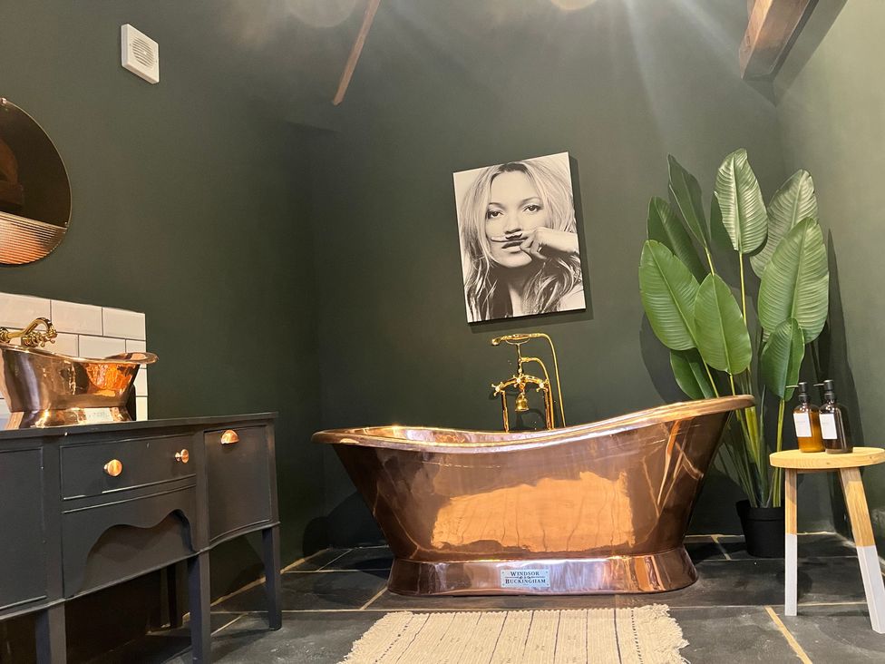 A bathroom with a copper bathtub and wooden vanity at Coach Lodge, Retford
