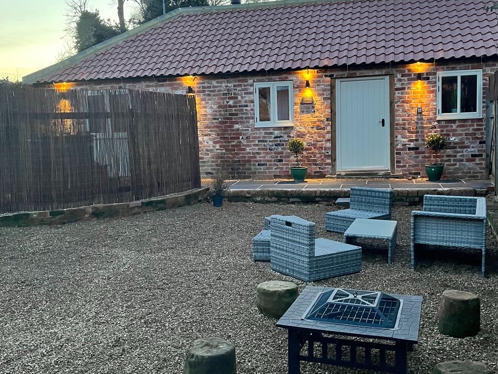 An outdoor space with a building, seating area, and gravel at Coach Lodge in Retford