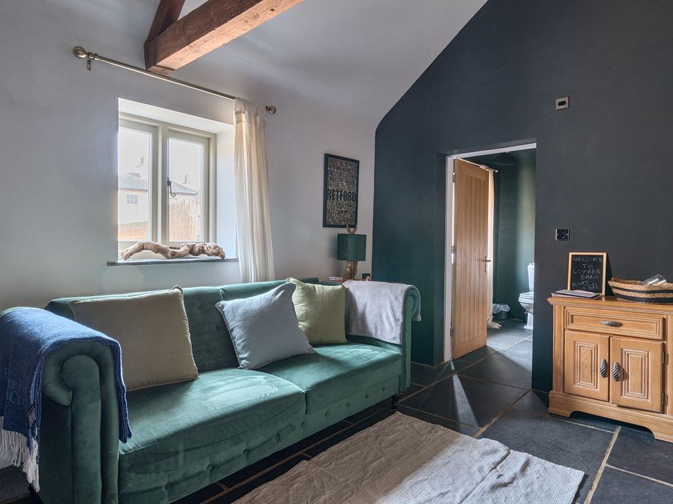 A sitting room with a sofa and a side table at Coach Lodge Retford