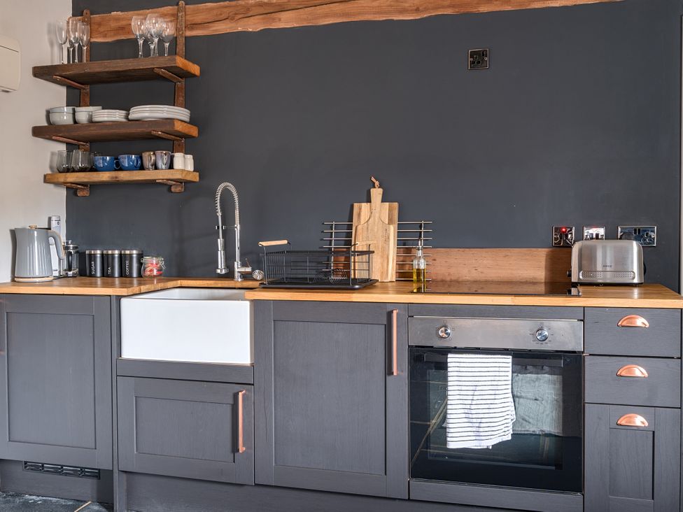 A kitchen with a sink, oven, and shelves at Coach Lodge in Retford