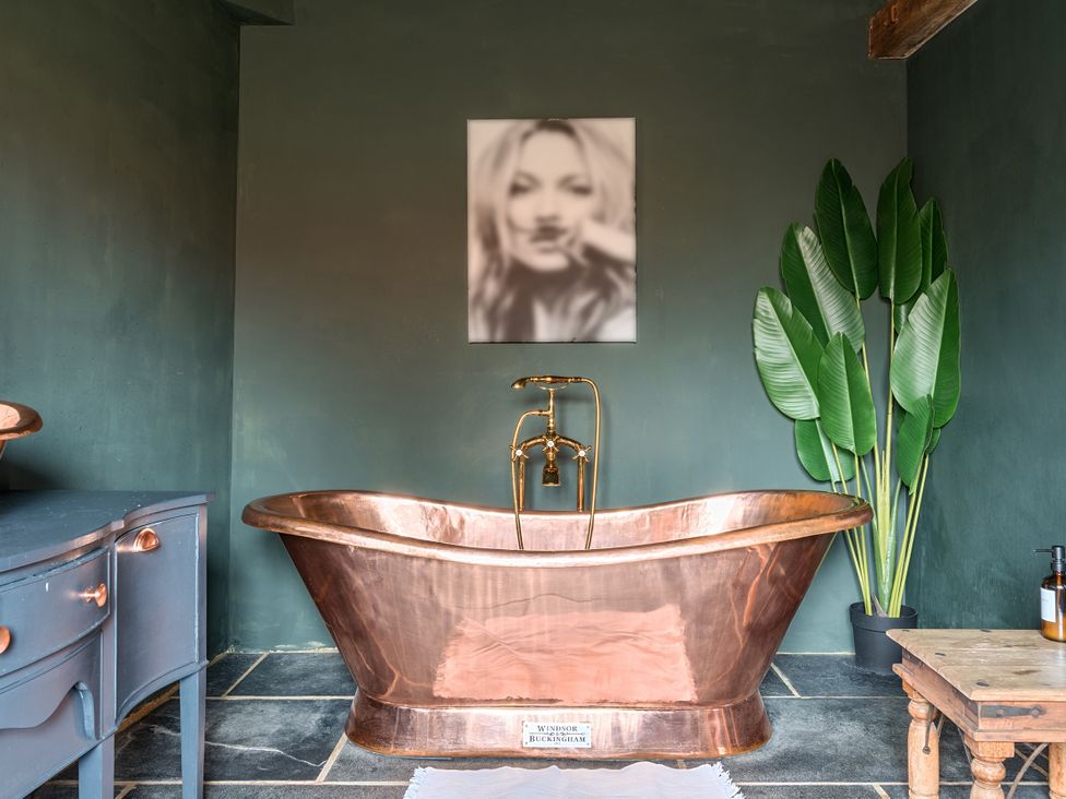 A bathroom featuring a copper bathtub and a potted plant at Coach Lodge in Retford