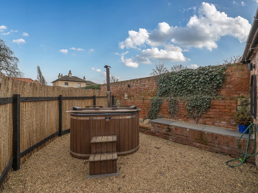 An outdoor area featuring a hot tub and stone wall at Coach Lodge in Retford