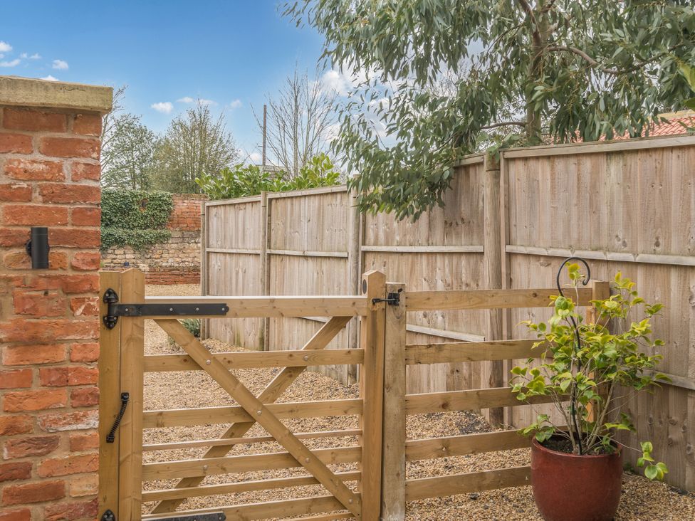 A garden with a wooden gate and fence at Coach Lodge in Retford