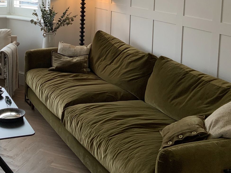 A living room with a green sofa and a lamp at 11 Sandhurst Avenue Lytham St. Annes