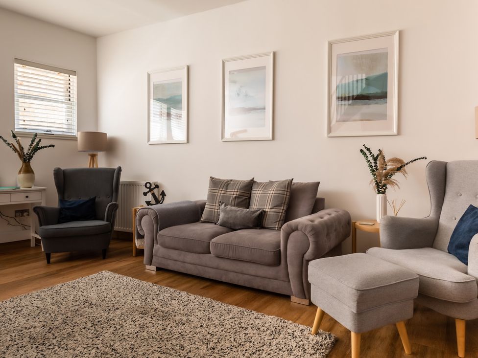 A living room with a sofa, armchairs, and wall art at 11A Cards Wynd Anstruther