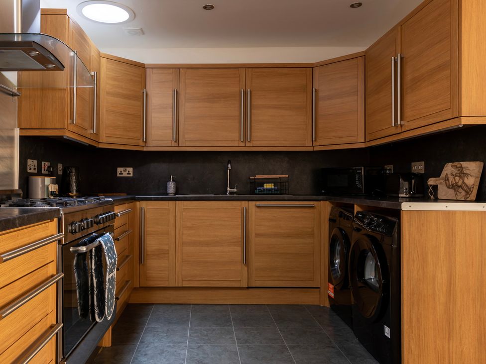 A kitchen with wooden cabinets and stainless steel appliances at 11A Cards Wynd Anstruther