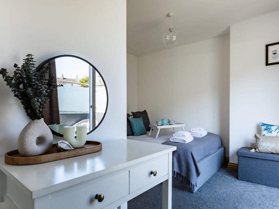 A bedroom with a bed, side table and mirror at 11A Cards Wynd Anstruther