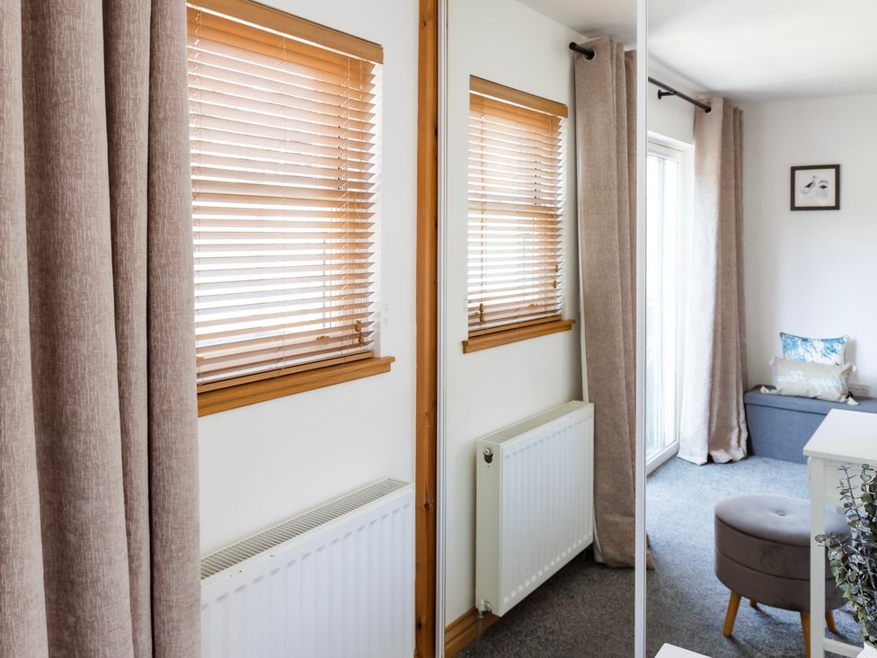 A living room with window blinds and a mirror at 11A Cards Wynd Anstruther