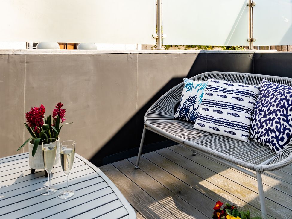 An outdoor seating area with cushions on a bench and glasses on a table at 11A Cards Wynd in Anstruther