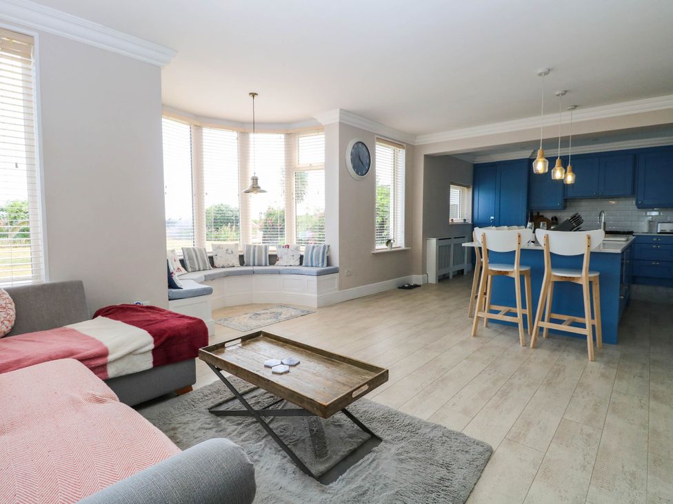 A living room with a blue kitchen and seating at Cootiya Corner in Great Lyth