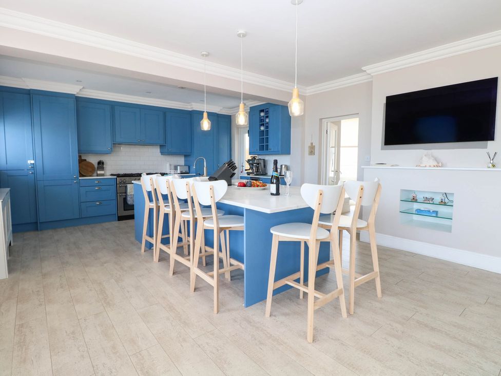A kitchen with blue cabinets and an island with bar stools at Cootiya Corner in Great Lyth