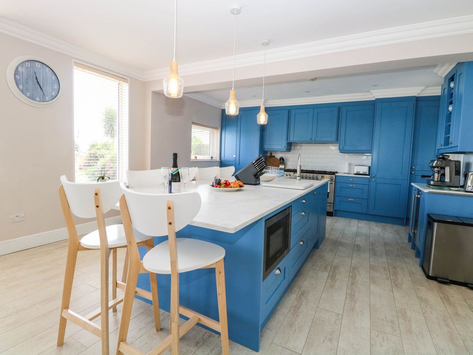 A kitchen with a blue island and bar stools at Cootiya Corner in Great Lyth