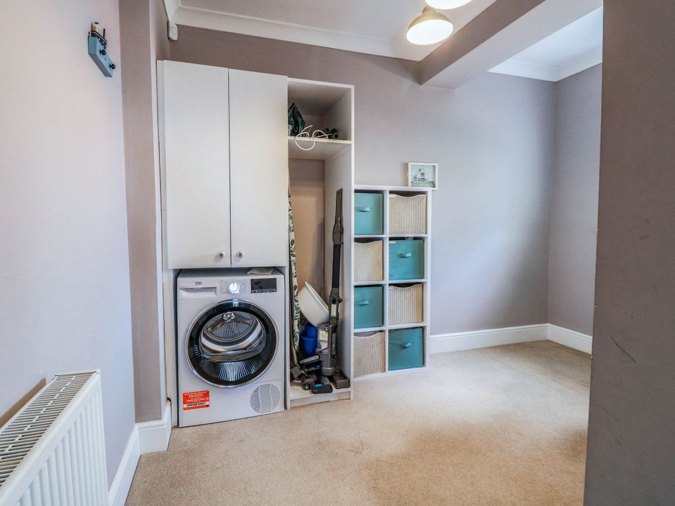 A utility room with a washing machine and storage cabinets at Cootiya Corner in Great Lyth