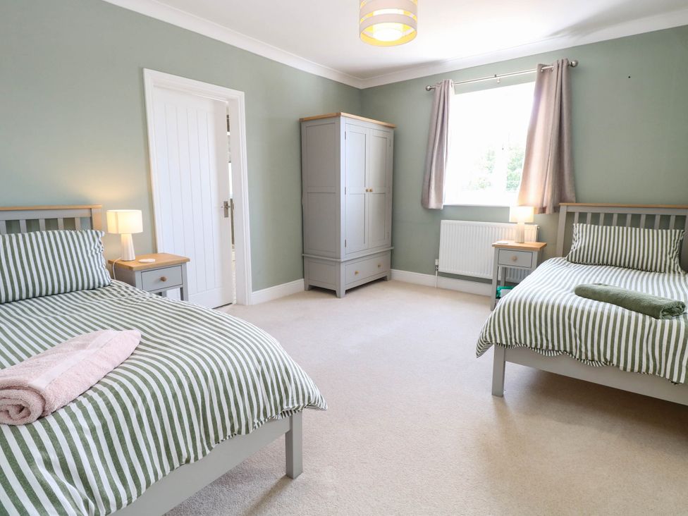 A bedroom with two beds and a wardrobe at Cootiya Corner in Great Lyth