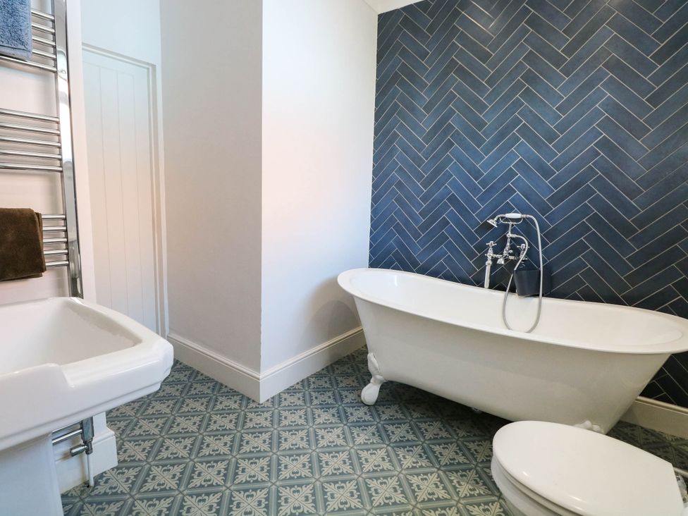 A bathroom with a bathtub, toilet, towel rail, and hand basin at Cootiya Corner, Great Lyth