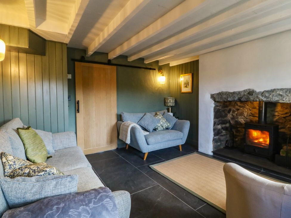 A living room with a fireplace and seating area at Seren Fach in Pwllheli