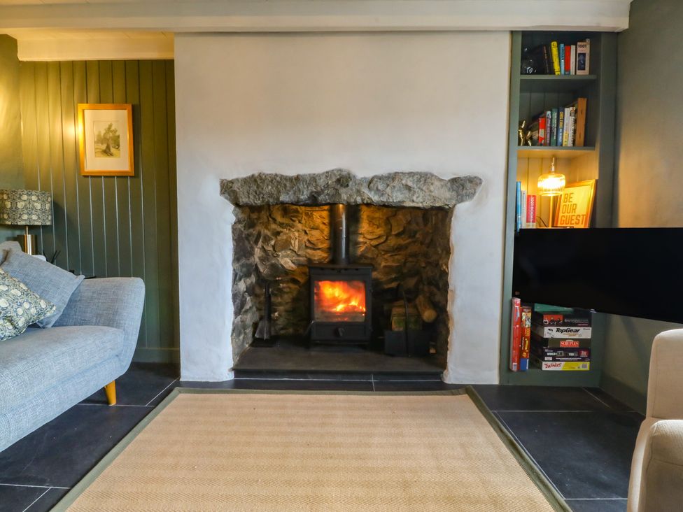 A living room with a fireplace and bookshelves at Seren Fach in Pwllheli